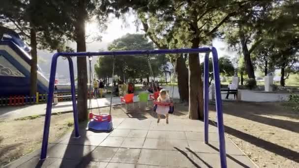 小さな女の子が遊び場の公園でチェーンスイングにスイングします 高品質4K映像 — ストック動画