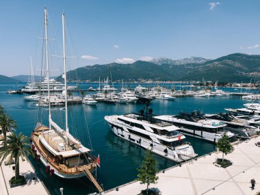 Sailing yacht stands at the pier next to the rows of motor yachts. High quality photo