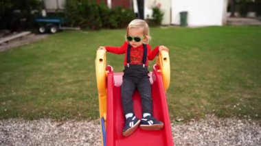 Little girl slides down a slide in the yard. High quality 4k footage