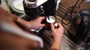 Süt sürahisinde kapuçino için süt köpürten bir adam. Yüksek kalite 4k görüntü