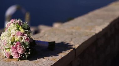 Bouquet of flowers lies on a stone fence. High quality FullHD footage