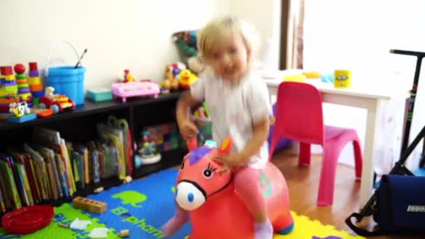 Little Girl Jumping Inflatable Horse Children Room High Quality Footage — Wideo stockowe