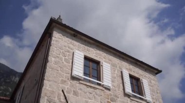 Stone facade of an old building with white shutters on the windows. Bottom view. High quality FullHD footage