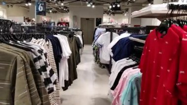 Rows with colorful t-shirts on hangers in a mall. High quality FullHD footage