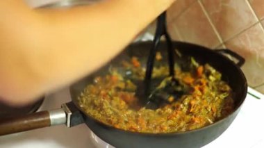 Chef stirs chopped vegetables stewing in a frying pan in oil. High quality 4k footage