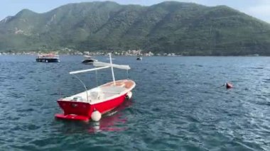 Small sailboat sways on the waves against the backdrop of mountains. High quality 4k footage