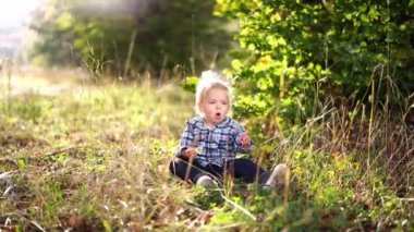 Little girl sits in a clearing with a chamomile in her hand and coughs. High quality 4k footage