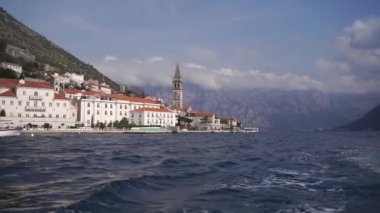 Deniz kıyısındaki eski evlerin arasında yüksek çan kulesi. Dobrota, Karadağ. Yüksek kaliteli FullHD görüntüler