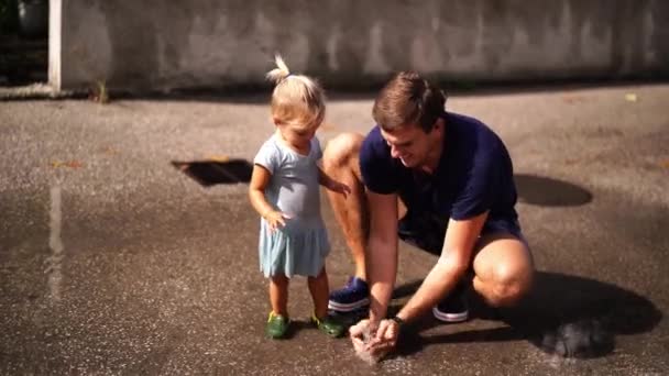 Dad Little Girl Squatted Puddle Splashes Water His Hands High — Vídeo de Stock