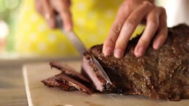 Cook cuts juicy roast beef into thin slices on a cutting board. High quality 4k footage