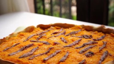 Pie with pumpkin and anchovies stands on a dish on the table. High quality 4k footage