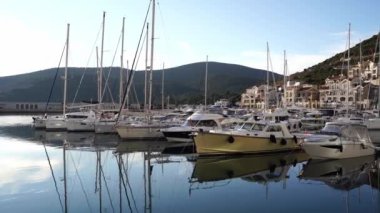 Sailing yachts stand at the pier near modern mansions against the backdrop of mountains. High quality 4k footage
