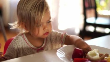 Little girl eating curly pasta with her hands at breakfast. High quality 4k footage