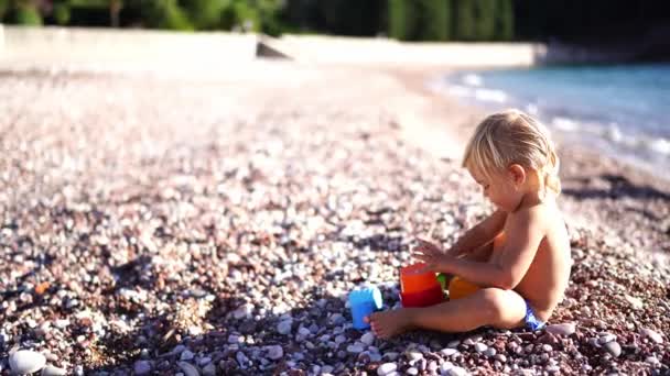 Menina Empilha Baldes Brinquedo Enquanto Sentado Praia Imagens Alta Qualidade — Vídeo de Stock