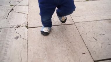 Küçük çocuk minicik ayakkabılarla fayansların üzerinde yürür. Kırpılmış. Yüksek kaliteli FullHD görüntüler