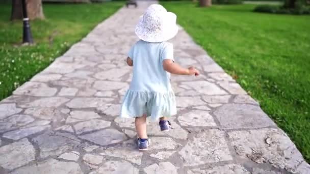 Κοριτσάκι Καπέλο Παναμά Περπατά Ένα Πλακόστρωτο Μονοπάτι Στον Κήπο Παραπαίοντας — Αρχείο Βίντεο