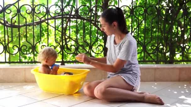 Mom Splashes Rubber Duckies Little Girl Sitting Bowl Water High — Stockvideo