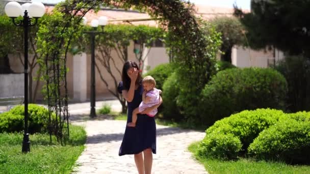 Mama Nosi Małą Dziewczynkę Ramionach Parku Coś Jej Mówi Wysokiej — Wideo stockowe