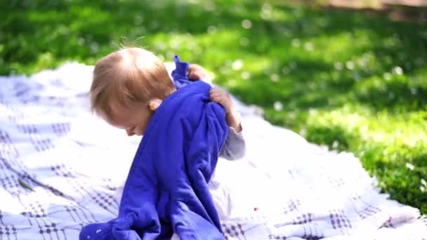 Small Baby Sits Blanket Green Grass Tries Put Sweater High — Video Stock