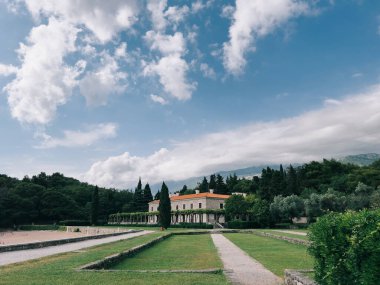 Sandy beach and green garden near the ancient villa Milocer at the foot of the mountains. Montenegro. High quality photo
