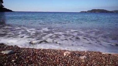Sea surf rolls on a gravel beach with colorful stones. High quality FullHD footage