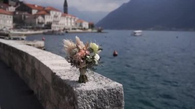 Bouquet of flowers stands on a stone fence on the embankment of the town of Dobrota. Montenegro. High quality FullHD footage