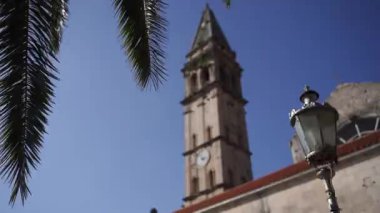 Green palm branch against the background of the bell tower of the Church of St. Nicholas. Perast. High quality FullHD footage