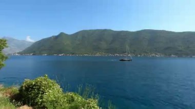 Yelkenli, mavi denizde yeşil dağların arka planına karşı yelken açar. Panorama. Yüksek kalite 4k görüntü