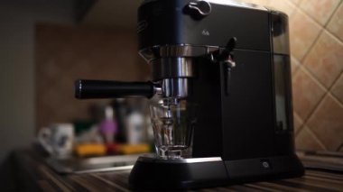 Black coffee dripping from a coffee maker horn into a glass on a stand. High quality 4k footage