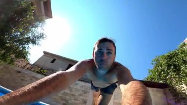 Genç adam kolları önde havuza atlıyor. Yüksek kaliteli FullHD görüntüler