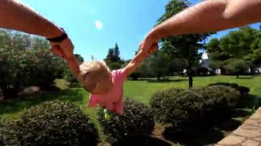 Dad is circling a little girl holding her hands in the park. High quality FullHD footage