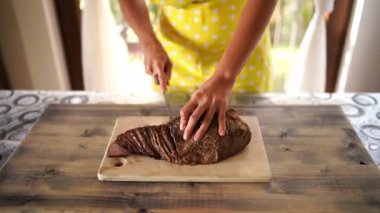 Woman cuts roast beef into slices and pushes the cut aside. High quality 4k footage