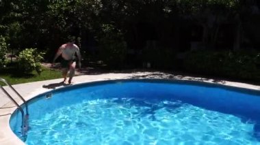 Man in swimming trunks raises his hands and jumps into the pool. High quality FullHD footage