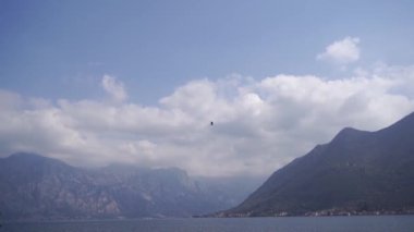 Kuş dağların arka planına karşı denizin üzerinde uçar. Yüksek kaliteli FullHD görüntüler