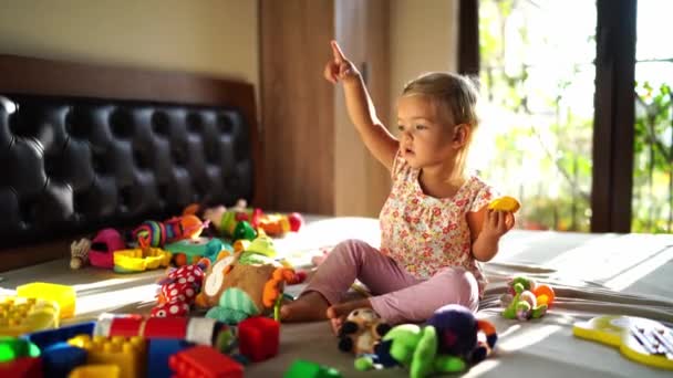 Meisje Speelt Met Een Veelkleurig Speeltje Zittend Tussen Zacht Speelgoed — Stockvideo