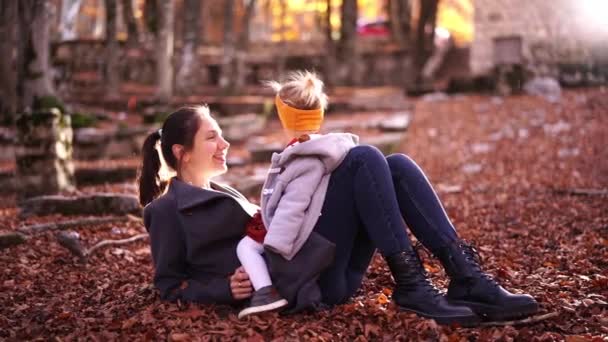 Little Girl Sits Her Mother Belly Lying Fallen Leaves Park — Vídeo de Stock