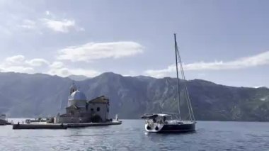 Sailboat stands near the island of Gospa od Skrpjela in the Bay of Kotor. High quality 4k footage
