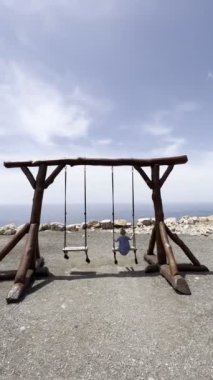 Little girl swings on a rope swing on wooden supports. High quality 4k footage