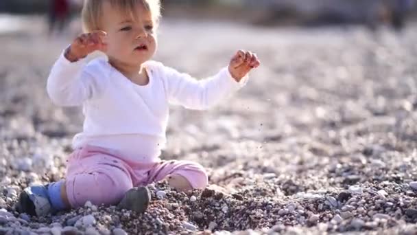 Κοριτσάκι Κάθεται Μια Παραλία Βότσαλα Ταξινομώντας Βότσαλα Χέρια Της Και — Αρχείο Βίντεο