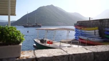 Stacked kayaks on a stone pier by the sea with mountain views. High quality FullHD footage