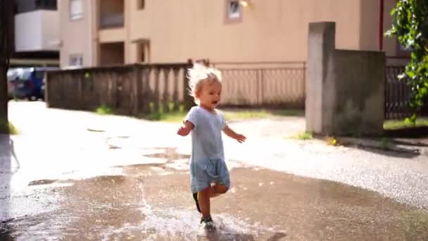 Маленькая Девочка Шлепанцах Бежит Через Лужи Дороге Поднимая Брызги Высококачественные — стоковое видео