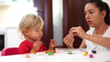 Mom teaches a little girl to sculpt crafts from plasticine while sitting at the table. High quality 4k footage