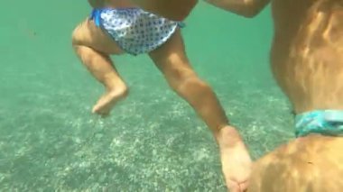 Mom teaches a small child to swim underwater holding his armpits. High quality 4k footage