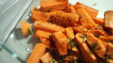Cook sprinkling spices on sweet potato slices on a platter. High quality 4k footage