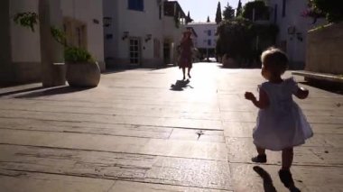Little girl runs around the yard waving her arms towards her mother. High quality FullHD footage