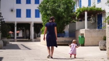 Annem ve küçük bir kız evin avlusunda yürüyorlar. Arkadan bak. Yüksek kalite 4k görüntü