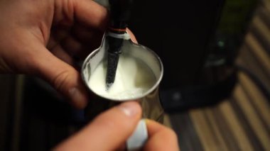 Man frothing milk in a jug with a coffee machine tube. High quality 4k footage