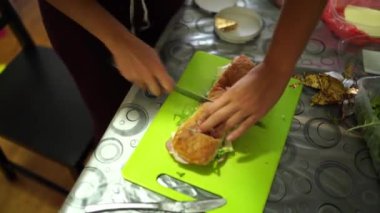 Chef cuts a large sandwich in half and is about to wrap it in cling film. High quality 4k footage