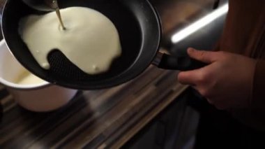 Man pours a ladle of batter into a frying pan and distributes it. High quality 4k footage