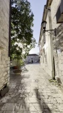 Narrow street of an old town by the sea with a paved road and stone houses. High quality 4k footage